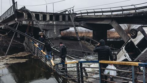 Varios civiles cruzan por el puente bombardeado en Irpin, Ucrania