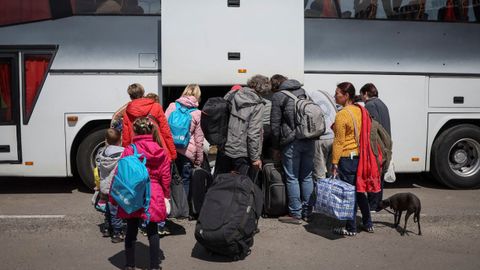 Refugiados ucranianos de Mariúpol cargan sus equipajes en un autobús con destino a Polonia