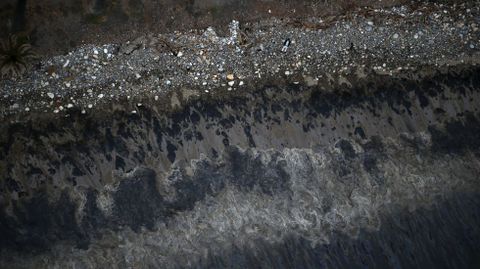 Un hombre observa una mancha de aceite en una playa del estado de California, donde una tubera rota ha derramado miles de litros de petrleo al oceno. 