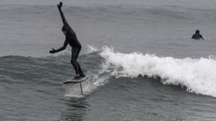 Un hombre hace surf en la Playa de San Lorenzo en Asturias