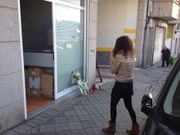 Una viandante observa las flores y velas en  memoria de la agente