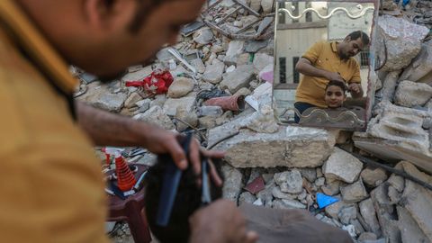 Un palestino corta el pelo a un nio entre las ruinas de un edificio en Gaza