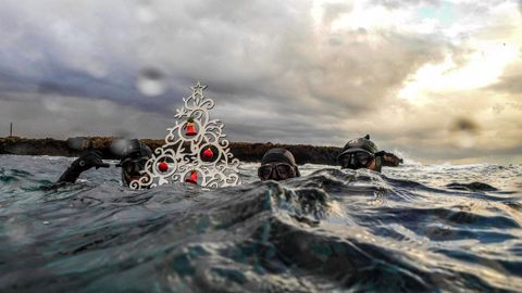 Tres buzos muestran un rbol de Navidad en la costa de la ciudad de Trpoli, en Lbano