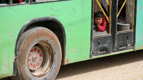 Un nio sirio descansa en el interior de un autobs destartalado, en Rashidin
