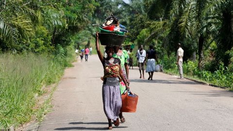Una mujer lleva sus posesiones sobre la cabeza en Congo..Una mujer carga sus pertenencias sobre la cabeza en Congo