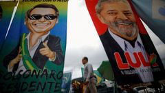 Un hombre camina en Brasilia entre dos carteles electorales de los aspirantes a la presidencia de Brasil