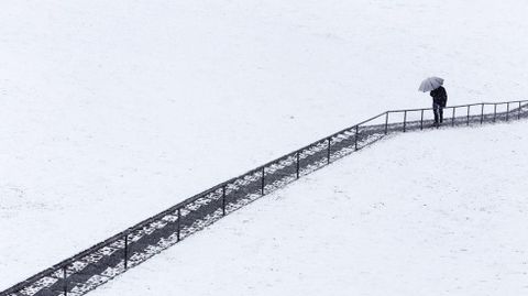 Un hombre sube unas escaleras bajo una intensa nevada cada en vila.