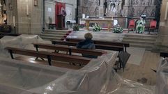 Una mujer asiste a una de las misas de esta semana entre los plásticos que cubren los bancos de la parte frontal de la iglesia del Cardenal