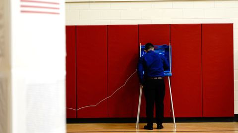 Un hombre completa su papeleta en un colegio electoral dentro de un escuela de Racine, en Wisconsin