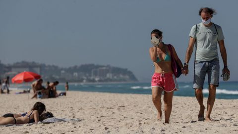 Una pareja con mascarillas camina en la playa de Barra de Tijuca, en Ro de Janeiro (Brasil)