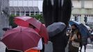 Unos turistas se protegen de la lluvia junto a una estatua de Úrculo, en Oviedo