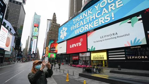 Una mujer se toma una selfie mientras los letreros de agradecimiento aparecen en las vallas publicitarias en un Times Square casi desierto durante la pandemia de Covid-19, en Nueva York, EE.UU