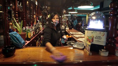 Una camarera limpia la barra en una cafetera de Monforte