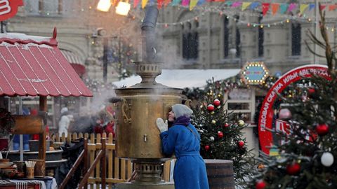 Una mujer se calienta las manos en un dispensador de agua caliente tradicional en el mercadillo de Navidad instalado en la plaza Roja de Mosc