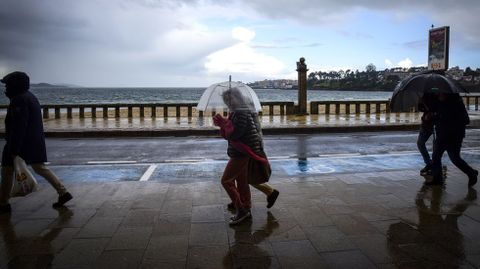 Turistas protegindose de la lluvia en el paseo martimo de Silgar.