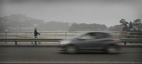 Un automvil y una peatona transitan por el puente del Pasaje durante un da de niebla. 