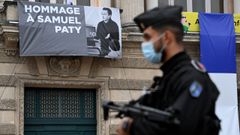 Un policia pasa al lado de un cartel en homenaje al profesor decapitado por un islamista