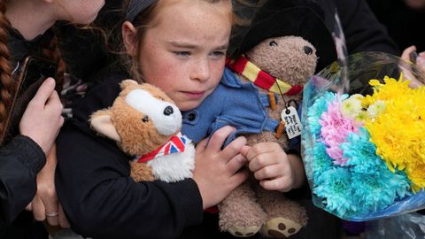 Una niña sujetando dos peluches, entre ellos un oso Paddington, en la procesión del féretro de Isabel II hasta la catedral de Giles.