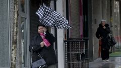 Una mujer y su paraguas pelean contra el viento esta mañana en A Coruña