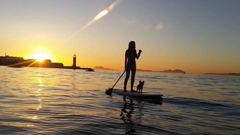 Un perro y su duea practicando paddle surf en la playa de Bouzas (Vigo)