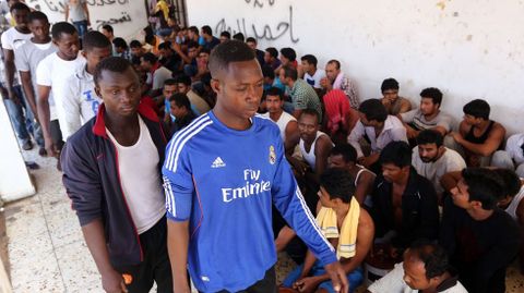 Inmigrantes rescatados por la guarda costera de Libia despues de que su barco se hundiese esperan en un centro de refugiados cercano a Tripoli