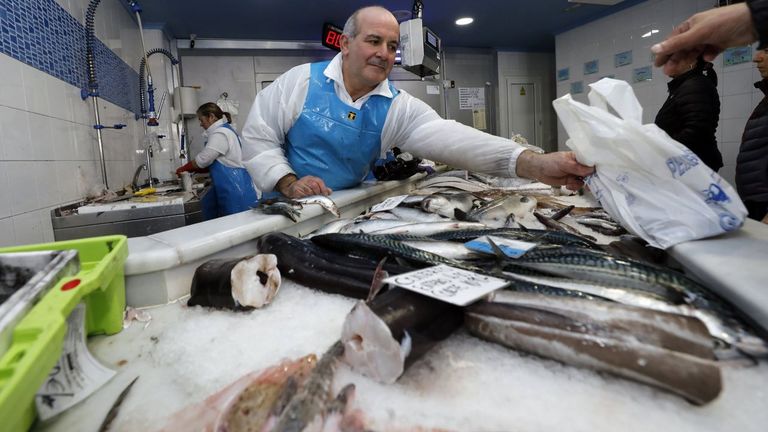 Un pescadero entregándole la compra en una bolsa a un cliente, pero ahora también puede llevarse su táper para recoger pescados y mariscos (foto de archivo)
