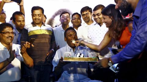 El exfutbolista Pel, que se encuentra en un acto  promocional en India, come un pedazo de tarta que le ofrecen unos seguidores por su cumpleaos, a la vuelta de la esquina. 