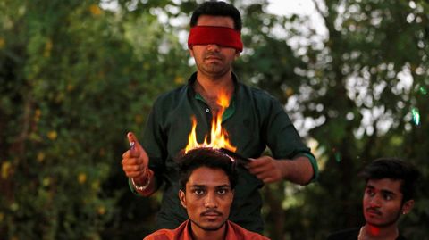 Vishnu Limbachiya, un peluquero muy particular, corta el pelo con fuego a un hombre en un parque en Ahmedabad (India).