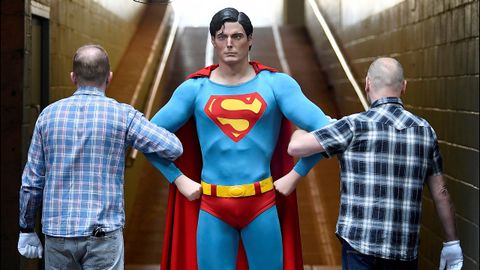 Dos empleados trasladan, en Londres, una reproducción del Superman encarnado por Christopher Reeve en 1978 y 1980
