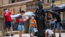 Varios turistas con mascarilla observan la escultura de la Regenta en la plaza de la catedral de Oviedo