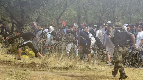 Inmigrantes, que llevaban esperando ms de 48 horas en la parte griega de la frontera, corren tras haber saltado la alambrada hacia el lado de Macedonia