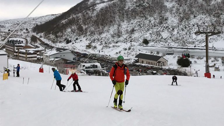 Los esquiadores disfrutan de la nieve con la estación de esquí de Valgrande-Pajares al fondo