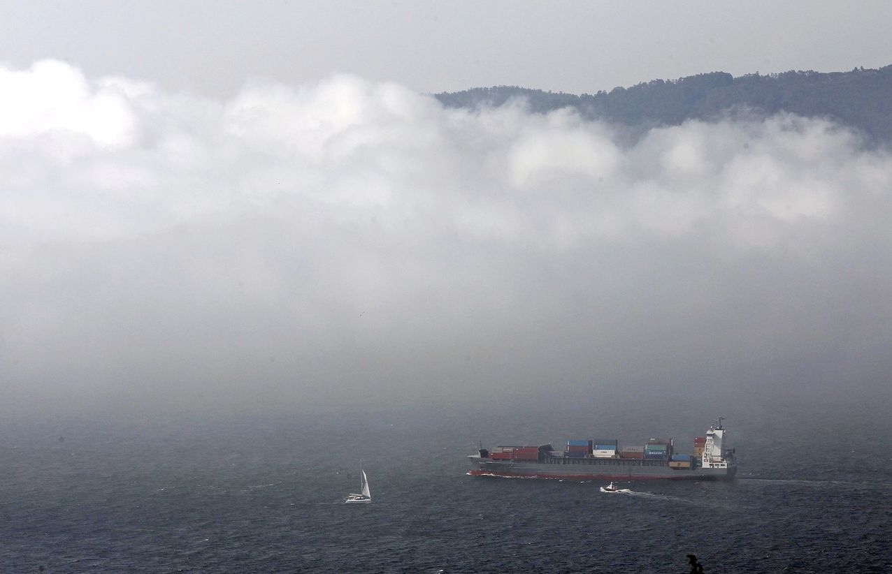 Un mercante se adentra en en el banco de niebla mientras sale al mar en la ría de Vigo
