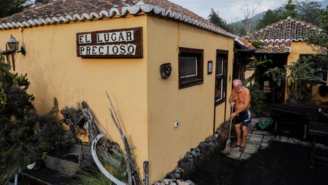Un hombre barre la ceniza esparcida en las inmediaciones de su vivienda, en Tacande de Arriba