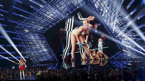 Miley Cyrus habla en el escenario con una imagen suya de fondo