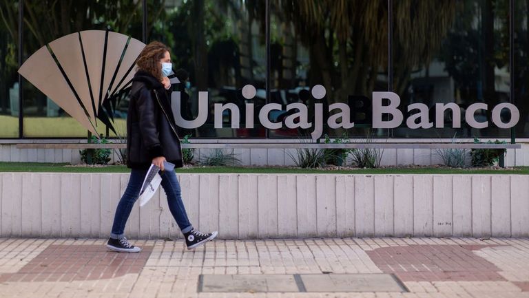 Una mujer pasa ante la sede de Unicaja en Málaga