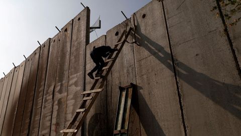 Un palestino escalando el controvertido muro israel para llegar a la oracin del viernes