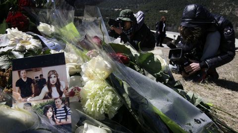 Periodistas toman imgenes de las flores y las fotos que se amontonan ante el monolito en homenaje a las vctimas, en Le Vernet.