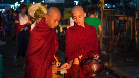 Monjes budistas comparten las notas de kyat que se les dan como limosna en un mercado de verduras al por mayor en Yangon (Myanmar)