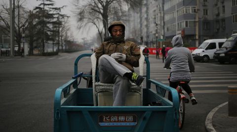 Un ciudadano chino sentado en una silla a bordo de un motocarro un brumoso da en Pekn (China).