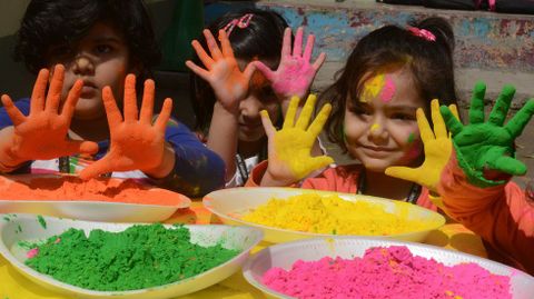 Nios indios con las manos pintadas en una escuela donde celebran el colorido y tradional Holi. 