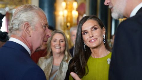La reina Letizia mira a su esposo, el rey Felipe VI, mientras este habla con Carlos III