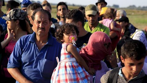 Inmigrantes sirios esperan el bus para ir a un campamento en Hungra, tras haber cruzado la frontera con Serbia