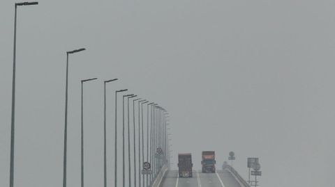 Dos camiones se cruzan en un puente malasio entre la neblina.
