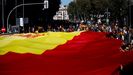 Decenas de personas sostienen la bandera de España de 1.000 metros cuadrados unos 130 kilos de peso, durante la concentración convocada por Vox 