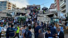 Ciudadanos y equipos de rescate buscan supervivientes en un edificio derruido en Esmirna