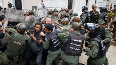 Miembros de la Guardia Nacional Bolivariana (GNB) forcejean con periodistas que intentan entrar al Palacio Federal Legislativo