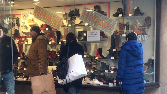 Compradores miran un escaparate con rebajas en el centro de Oviedo