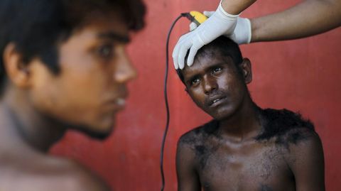 Un voluntario de Indonesia corta el pelo de un inmigrante de Bangladesh que intent entrar en el pas en una pequea embarcacin.