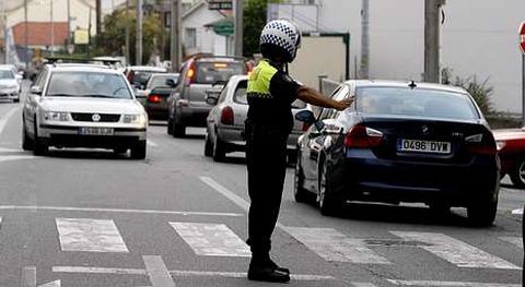 Un polica local regula el trfico en la carretera N-VI a su paso por Oleiros.